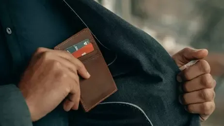 ผู้ชายกำลังหยิบซองในบัตรออกจากกระเป๋าเสื้อด้านใน