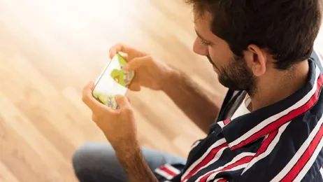 ผู้ชายกำลังนั่งเล่นเกมโทรศัพท์มือถือ